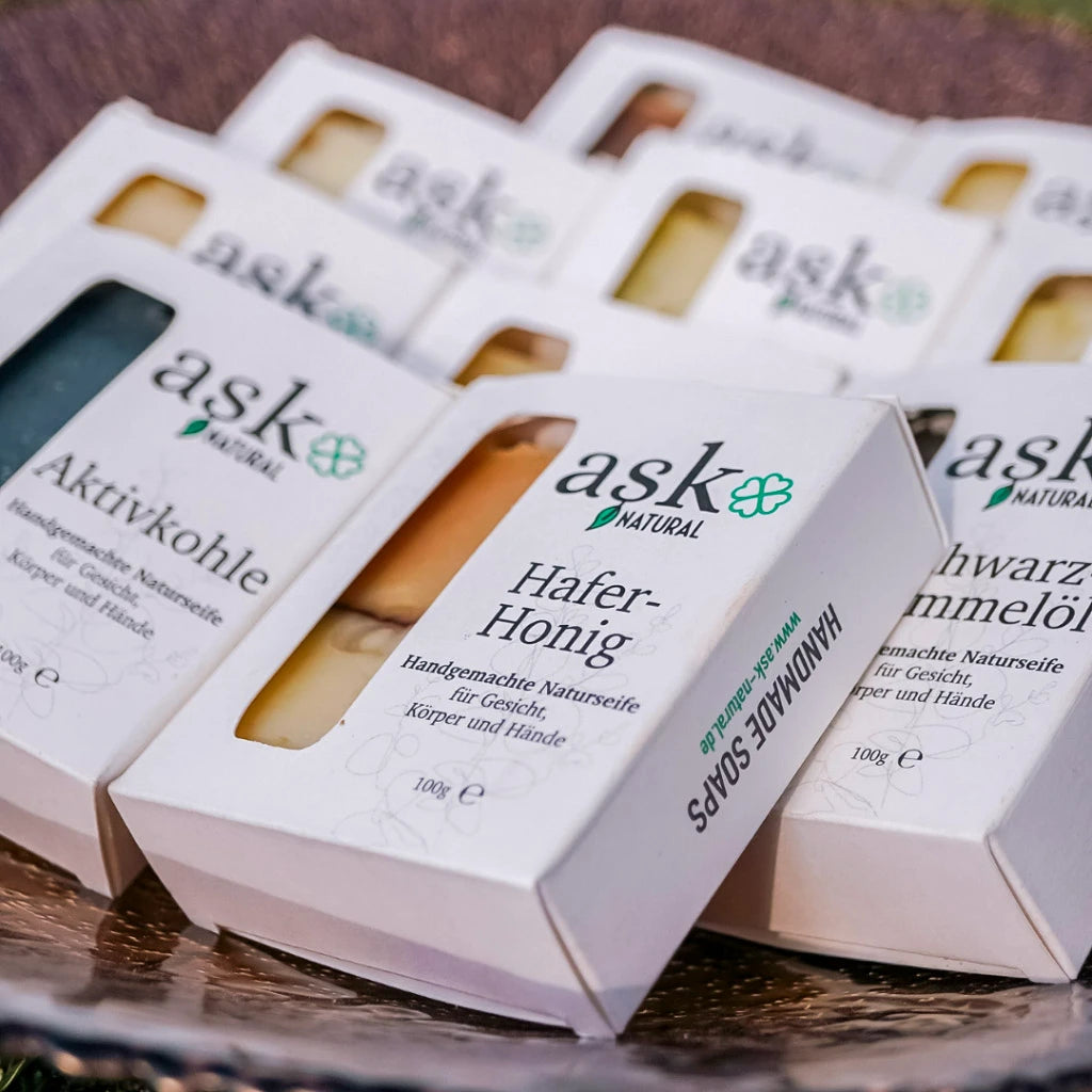 Hafer-Honig Seife in Verpackung mit verschiedenen Seifen im Hintergrund – Plastikfreie Verpackung.