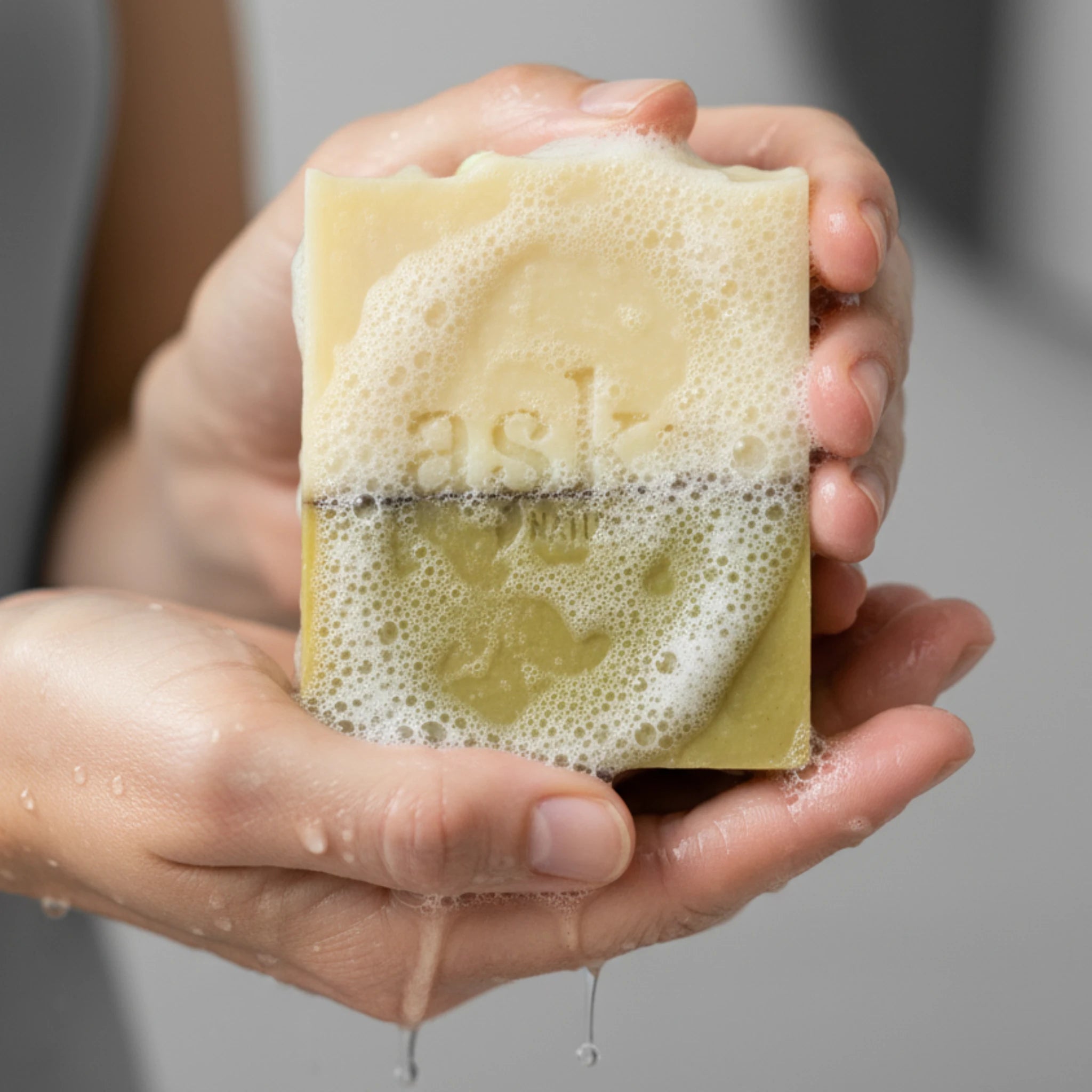 Nahaufnahme einer handgemachten Teebaumöl Seife von ASK Natural mit natürlicher Textur und cremigem Schaum in den Händen, hergestellt im traditionellen Kaltverfahren.