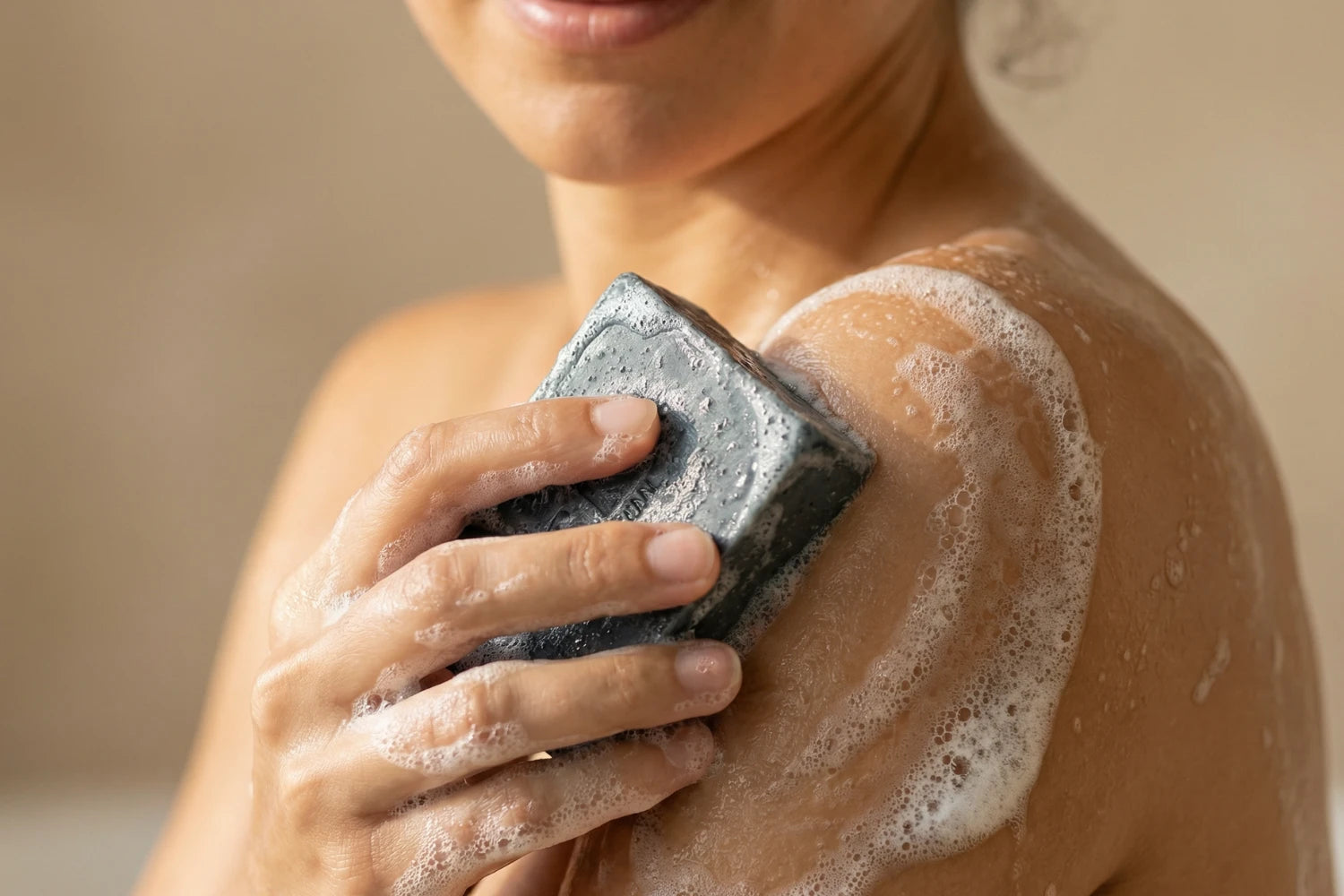 Anwendung einer handgemachten Aktivkohle Naturseife von ASK Natural bei der täglichen Hautpflege.
