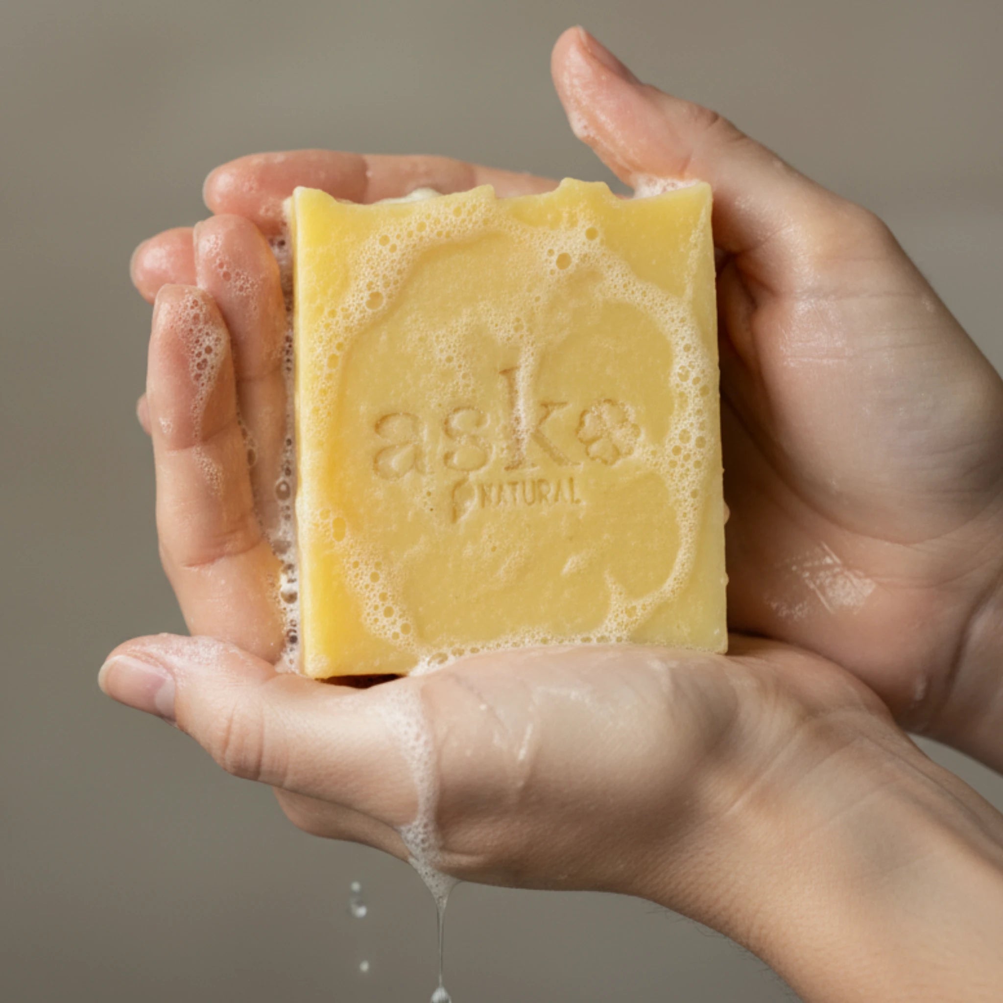 Nahaufnahme einer handgemachten Haarseife von ASK Natural mit natürlicher Textur und cremigem Schaum in den Händen, hergestellt im traditionellen Kaltverfahren.