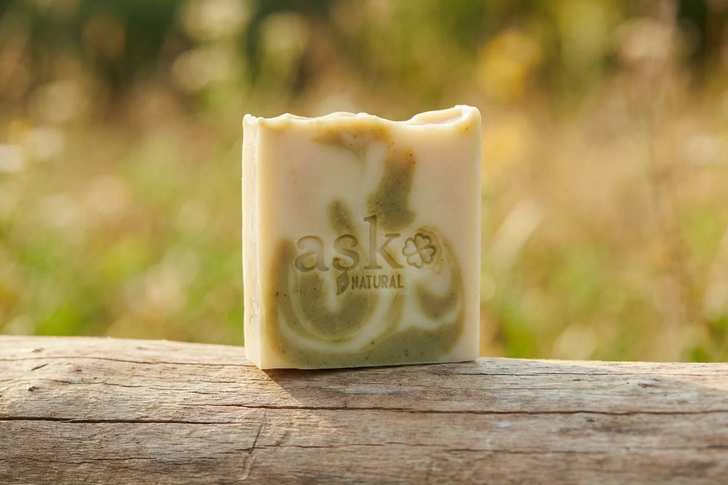 Handgemachte Aloe Vera Naturseife von ASK Natural - mit eingeprägtem Logo auf einem Holzstamm, vor natürlichem Hintergrund.