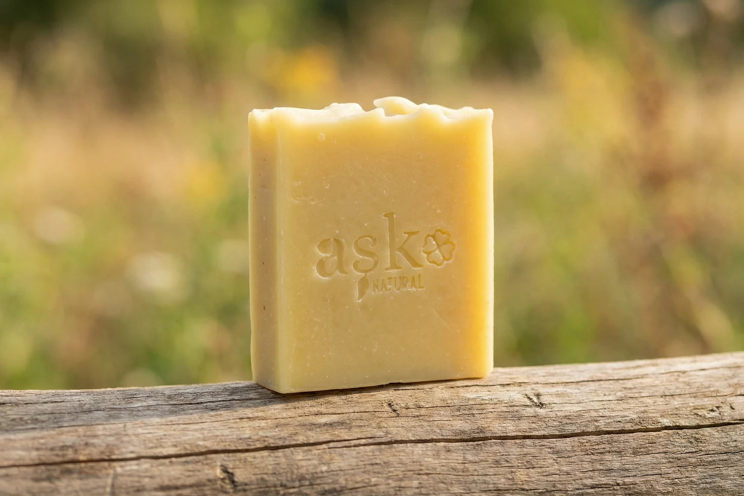 Handgemachte Haarseife von ASK Natural - mit eingeprägtem Logo auf einem Holzstamm, vor natürlichem Hintergrund.