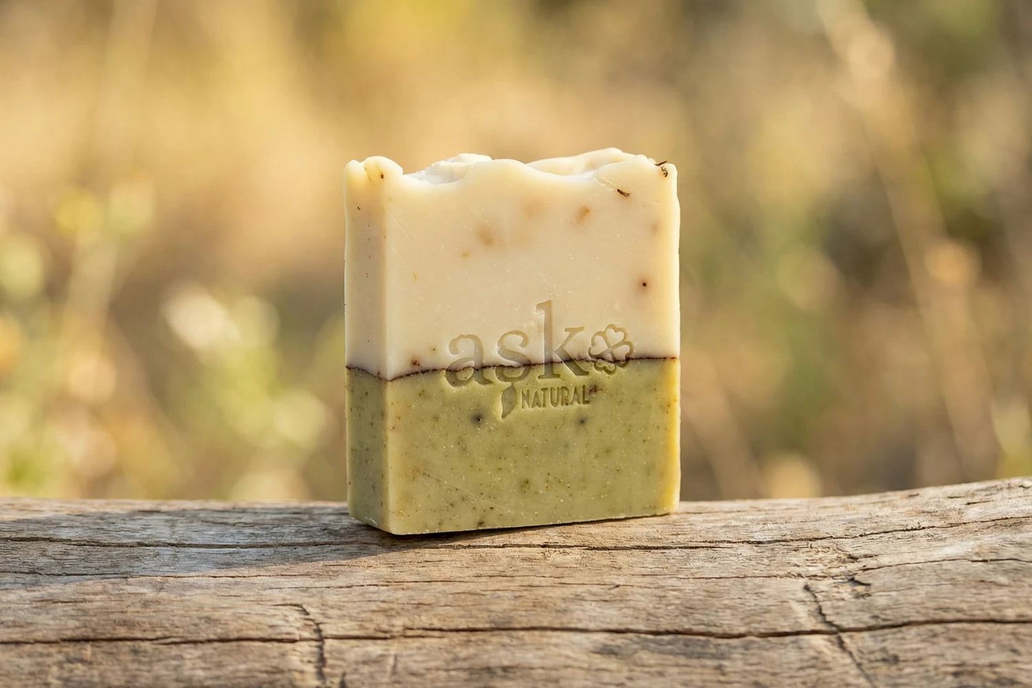 Handgemachte Lavendel Naturseife von ASK Natural - mit eingeprägtem Logo auf einem Holzstamm, vor natürlichem Hintergrund.