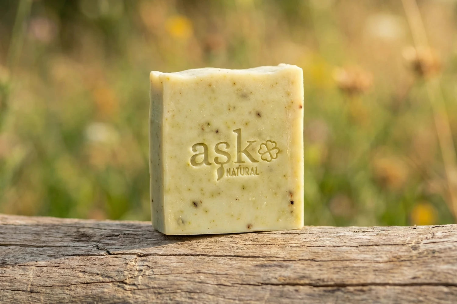 Handgemachte lorbeer Naturseife von ASK Natural - mit eingeprägtem Logo auf einem Holzstamm, vor natürlichem Hintergrund.