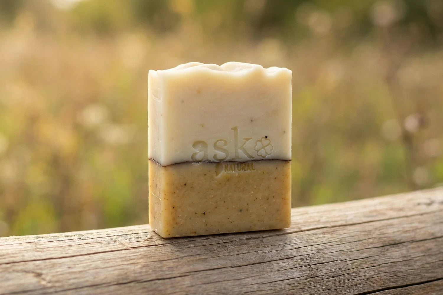 Handgemachte Patchouli-Lemon Naturseife von ASK Natural - mit eingeprägtem Logo auf einem Holzstamm, vor natürlichem Hintergrund.