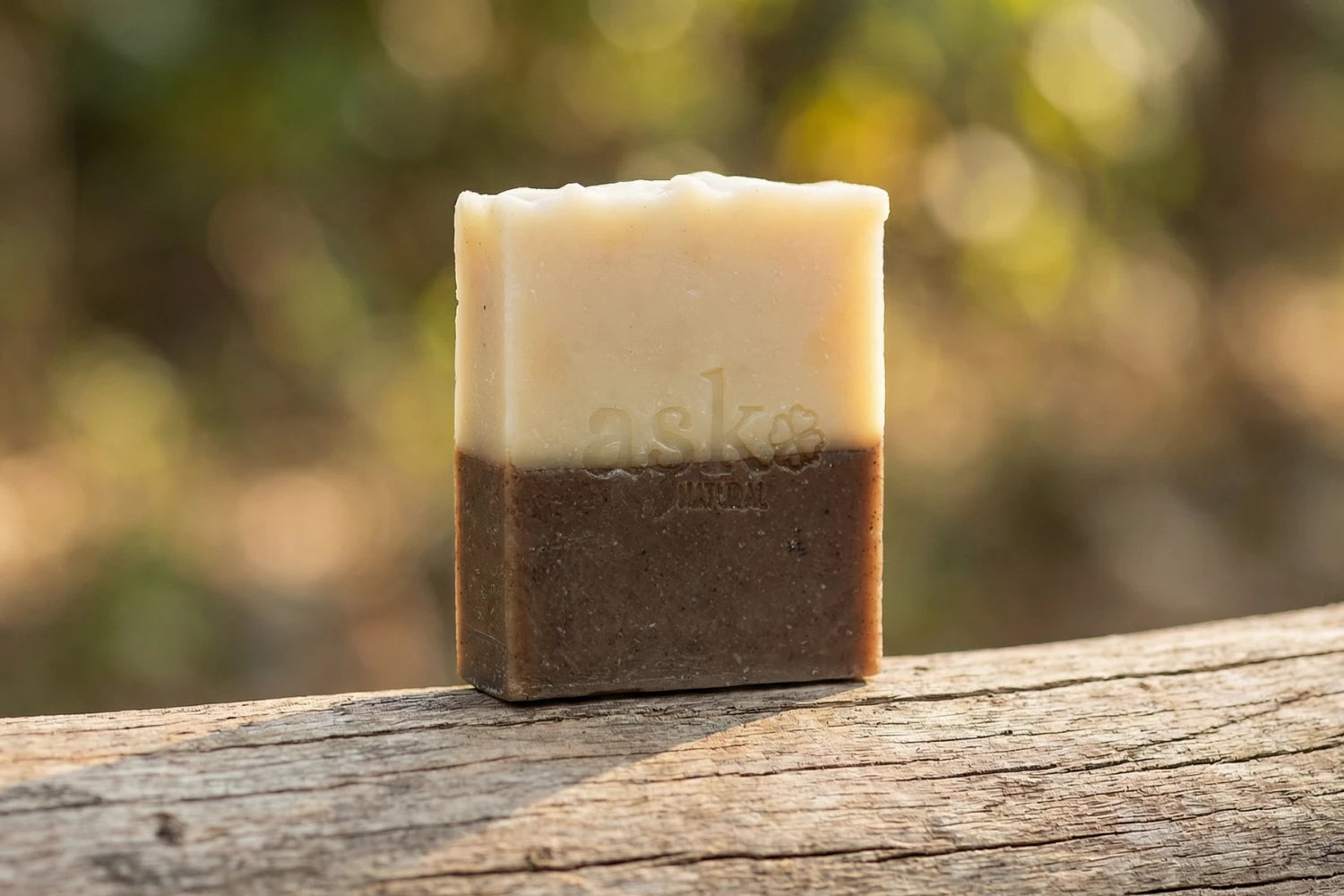 Handgemachte Zimt-Orange Naturseife von ASK Natural - mit eingeprägtem Logo auf einem Holzstamm, vor natürlichem Hintergrund.