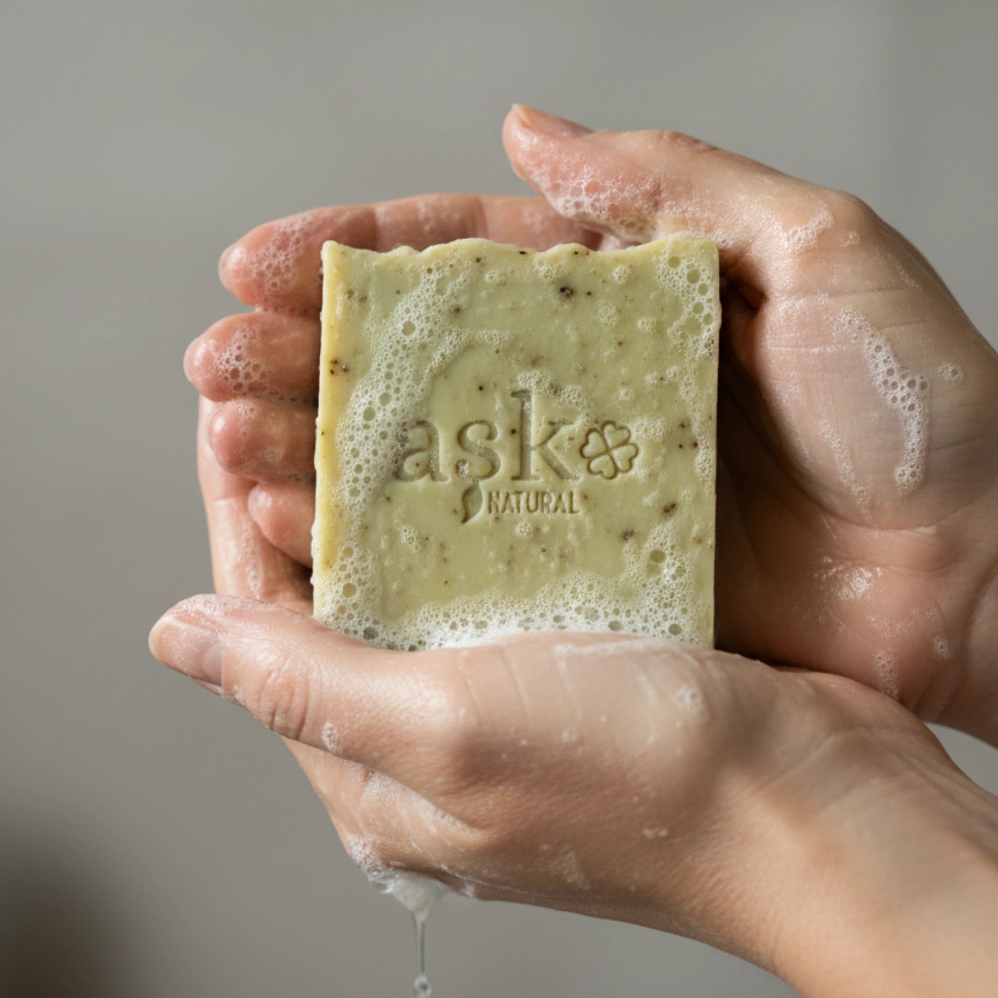 Nahaufnahme einer handgemachten Lorbeer Seife von ASK Natural mit natürlicher Textur und cremigem Schaum in den Händen, hergestellt im traditionellen Kaltverfahren.