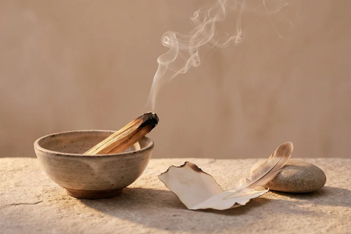 Palo Santo mit aufsteigendem Rauch neben einem gefalteten Zettel als Symbol für Loslassen.