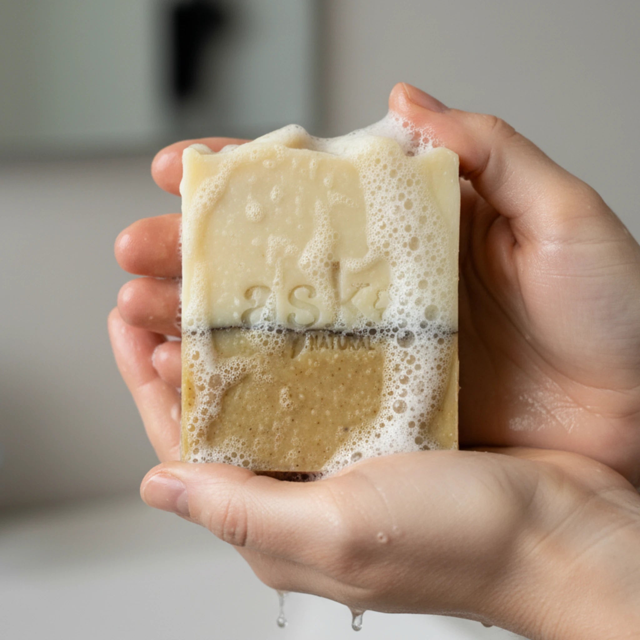 Nahaufnahme einer handgemachten Patchouli Lemon Seife von ASK Natural mit natürlicher Textur und cremigem Schaum in den Händen, hergestellt im traditionellen Kaltverfahren.