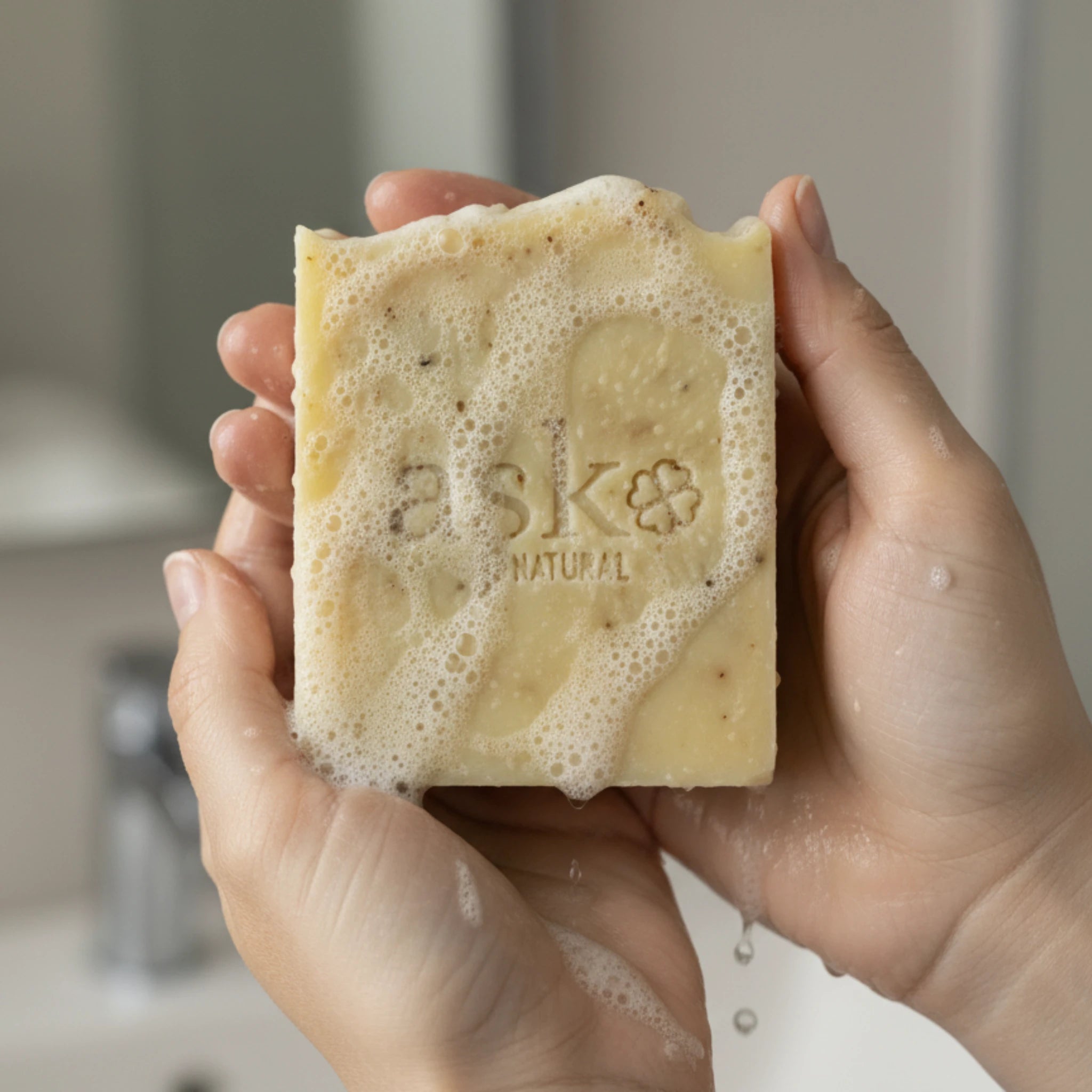 Nahaufnahme einer handgemachten Rosen Seife von ASK Natural mit natürlicher Textur und cremigem Schaum in den Händen, hergestellt im traditionellen Kaltverfahren.