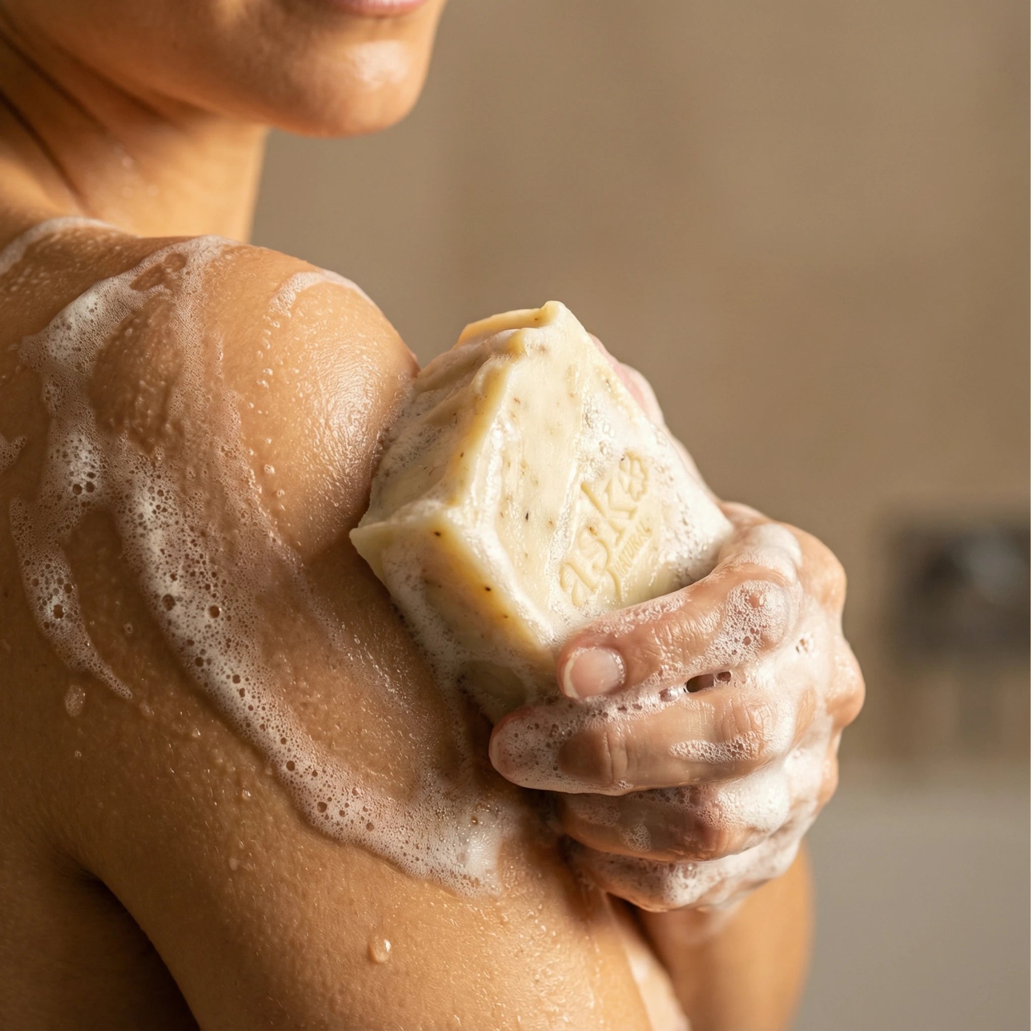 Frau hält handgemachte Rosen Seife von ASK Natural mit cremigem Schaum in den Händen während der Anwendung.