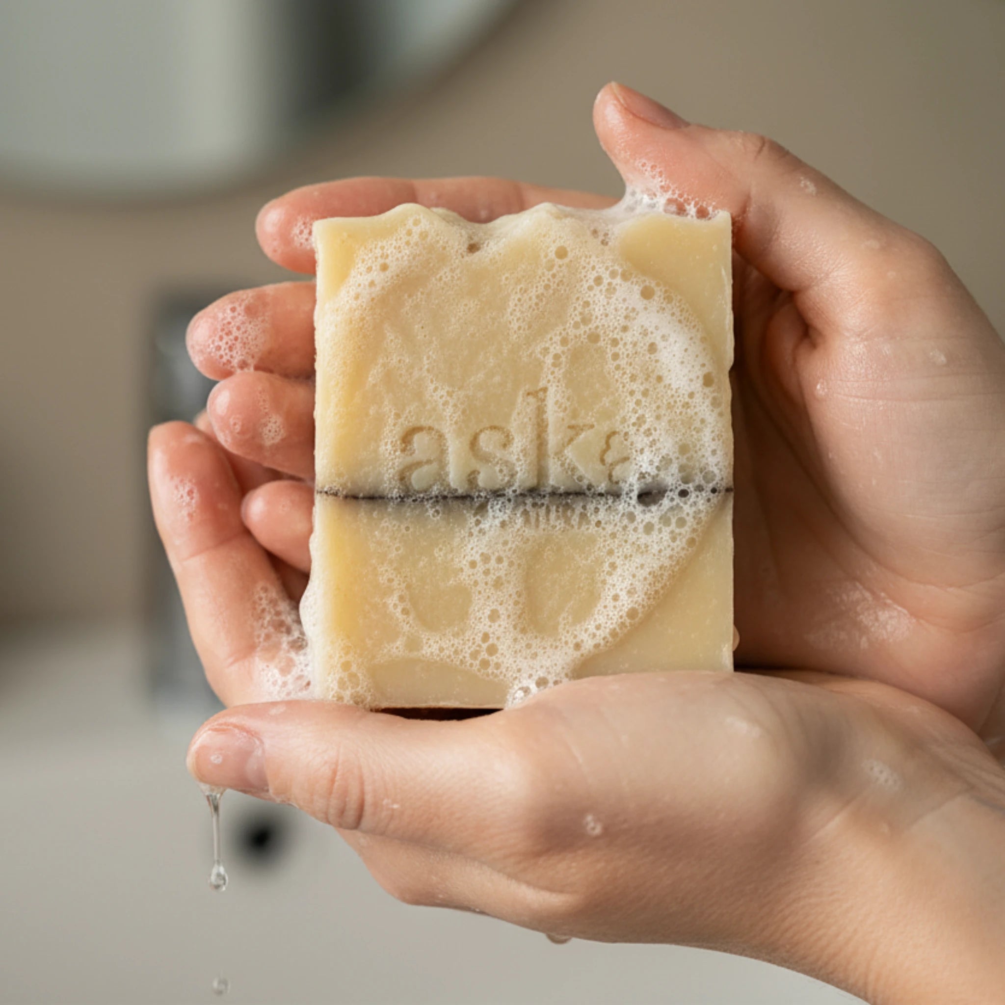 Nahaufnahme einer handgemachten Sheabutter Seife von ASK Natural mit natürlicher Textur und cremigem Schaum in den Händen, hergestellt im traditionellen Kaltverfahren.