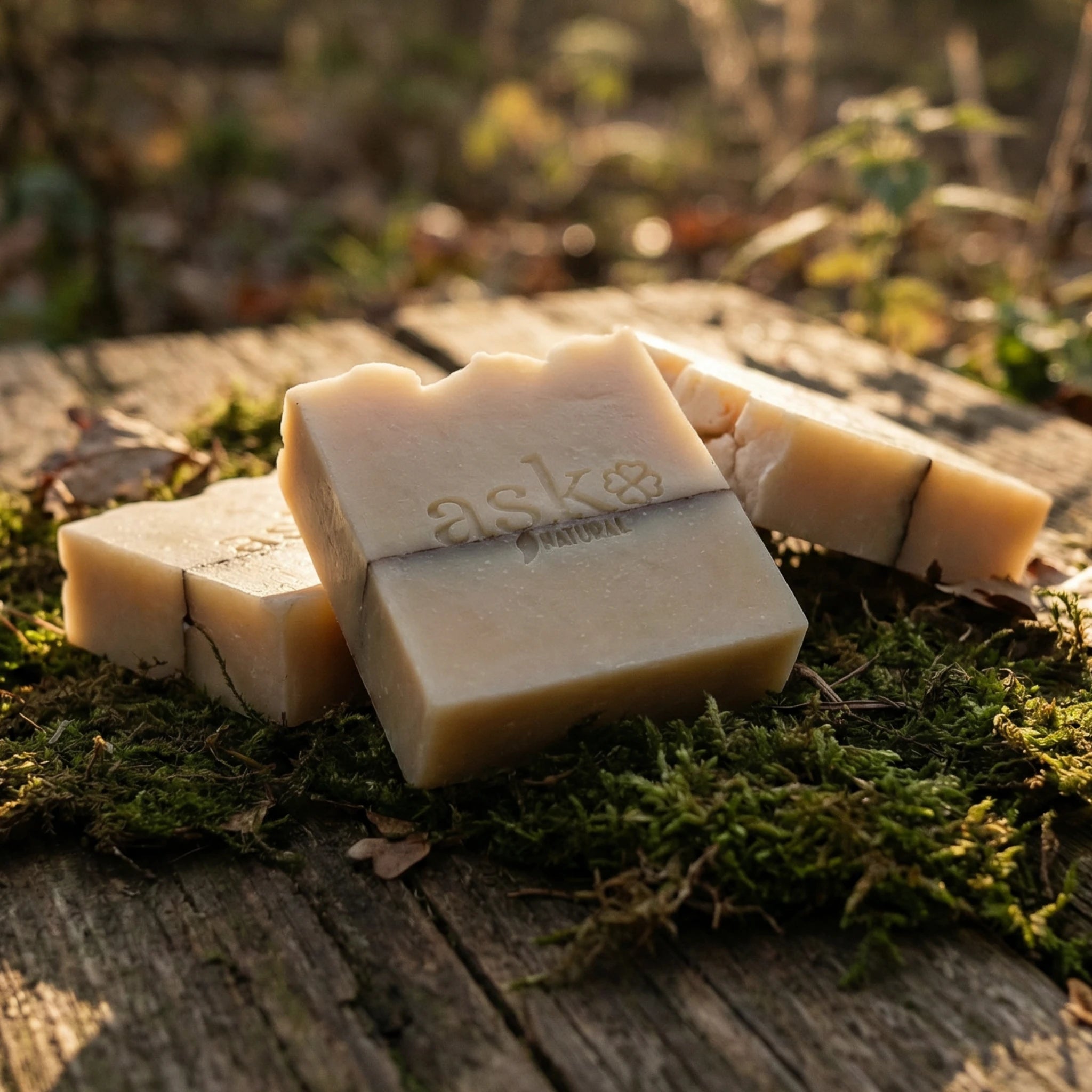 Mehrere handgemachte Sheabutter Seifen von ASK Natural als Set auf natürlichem Holz und Moos platziert, ideal für Kombination und Mengenrabatt.