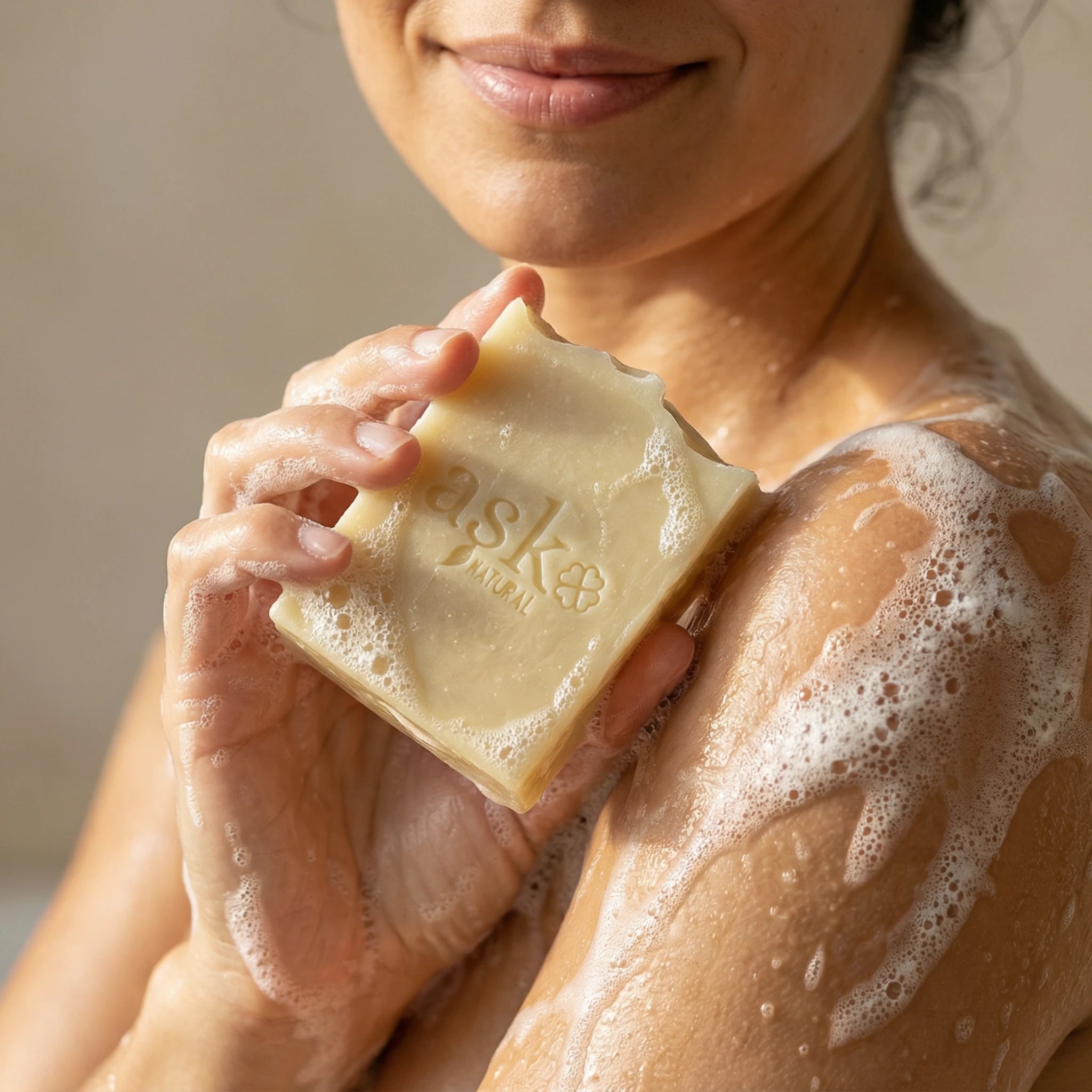 Frau hält handgemachte Ziegenmilch Seife von ASK Natural mit cremigem Schaum in den Händen während der Anwendung.
