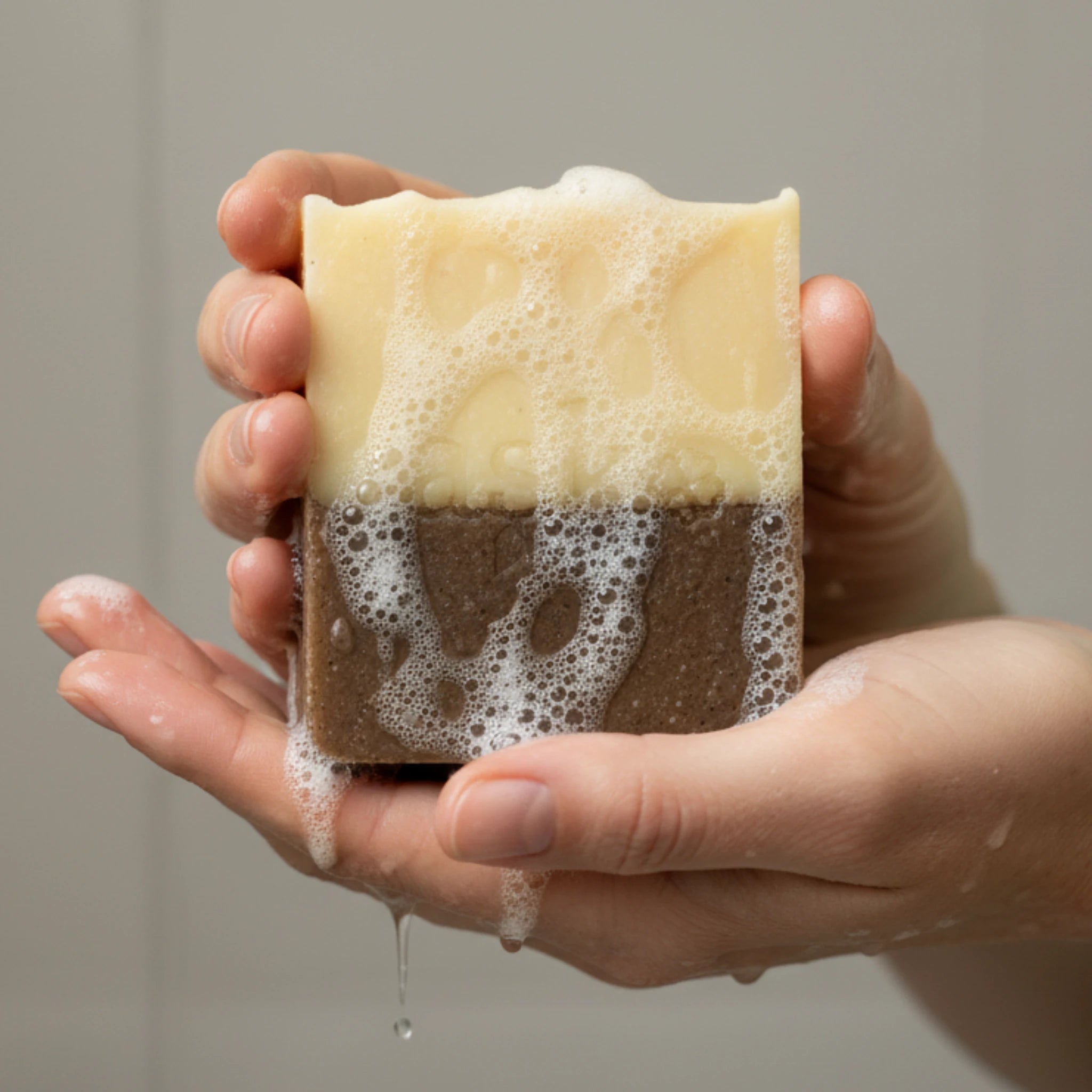 Nahaufnahme einer handgemachten Zimt Orange Seife von ASK Natural mit natürlicher Textur und cremigem Schaum in den Händen, hergestellt im traditionellen Kaltverfahren.